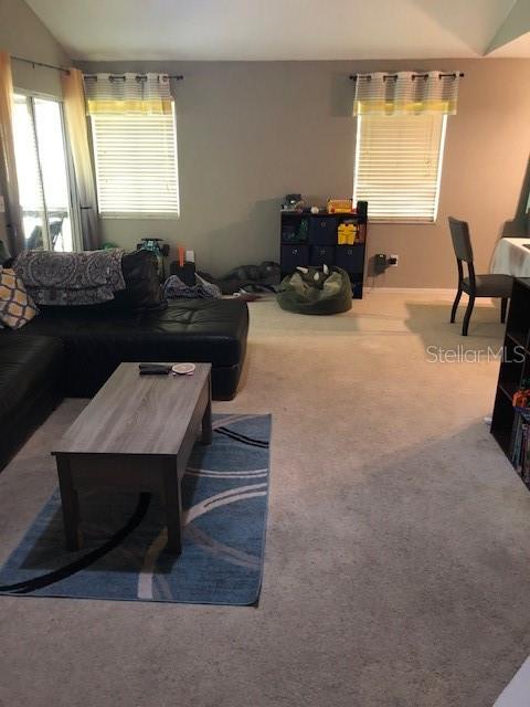 A living room features a black sectional sofa, a gray coffee table, and two windows — 2246 COACH HOUSE BOULEVARD UNIT 501, ORLANDO, FL