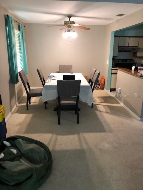 A dining room features a table with six chairs, a ceiling fan, and teal curtains — 2246 COACH HOUSE BOULEVARD UNIT 501, ORLANDO, FL