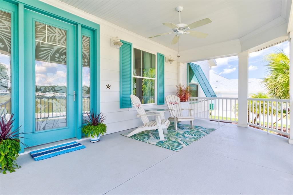 A covered front porch features a teal door, white siding, and two white Adirondack chairs — 1148 BAHIA HONDA KEY DRIVE, LADY LAKE, FL