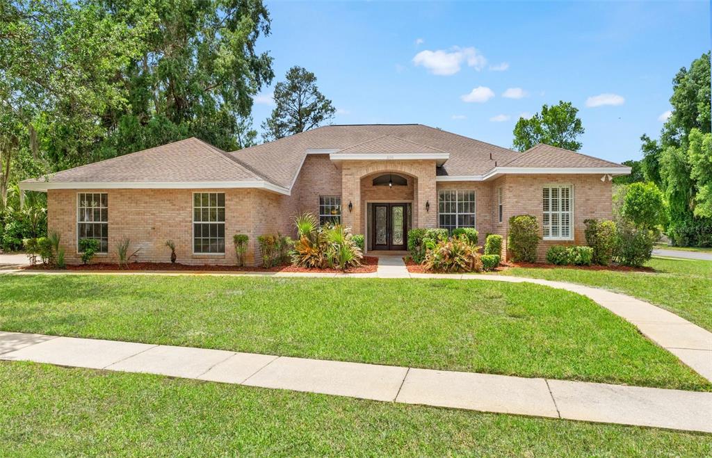 A single-story brick house with a hip roof and a central arched entryway — 6153 NEW OSPREY POINT, SPRING HILL, FL