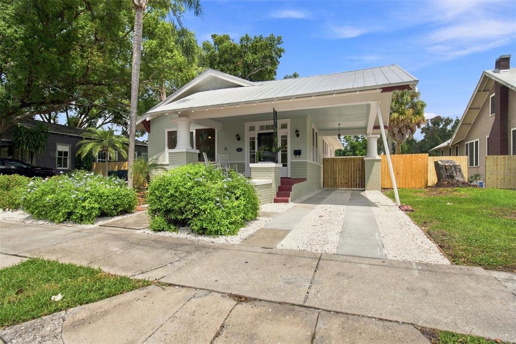 A light green bungalow with a metal roof, front porch, and attached carport — 2911 N CENTRAL AVENUE, TAMPA, FL