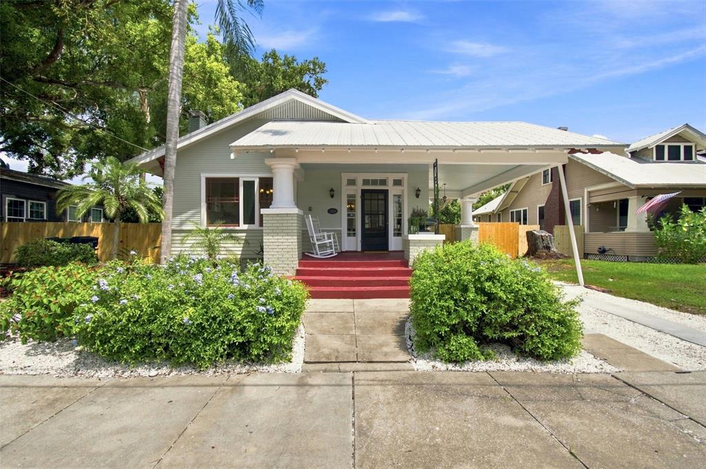 A light green bungalow with a metal roof, red front steps, and a covered carport — 2911 N CENTRAL AVENUE, TAMPA, FL