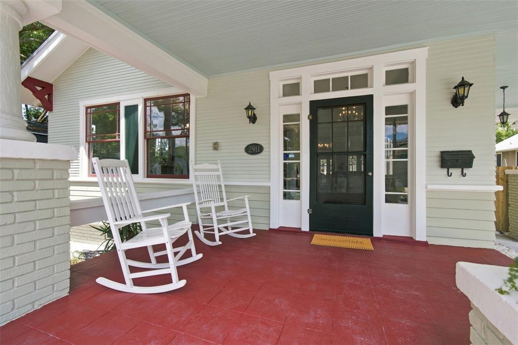 A covered front porch features a red floor, two white rocking chairs, and a dark door — 2911 N CENTRAL AVENUE, TAMPA, FL