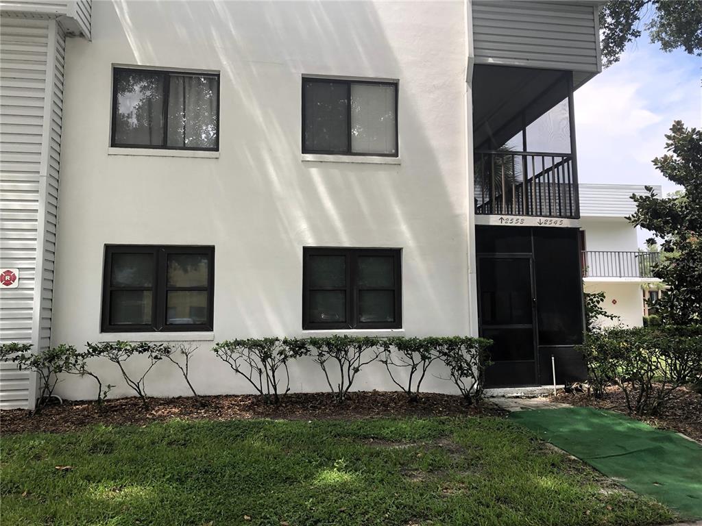 A kitchen features wood cabinets, laminate countertops, white appliances, and light-colored tile flooring — 2545 OAK PARK WAY UNIT 118, ORLANDO, FL