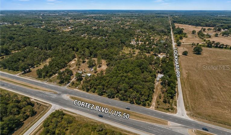 An aerial view shows the intersection of Cortez Boulevard and Lockhart Road near wooded land — 29373 CORTEZ BOULEVARD, BROOKSVILLE, FL