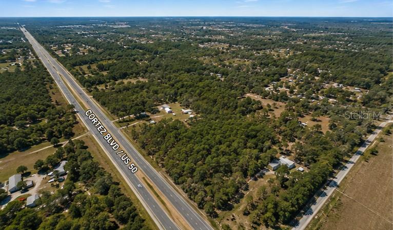 An aerial view shows a highway running alongside a large, wooded plot of land — 29373 CORTEZ BOULEVARD, BROOKSVILLE, FL
