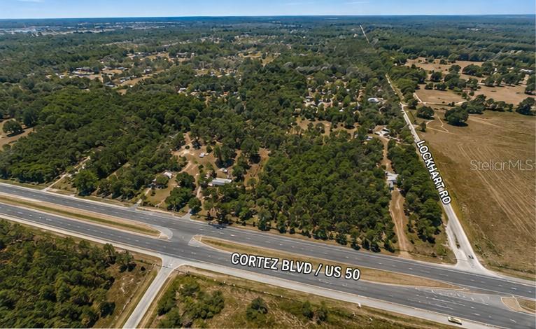 An aerial view shows a wooded lot at the intersection of a highway and road — 29373 CORTEZ BOULEVARD, BROOKSVILLE, FL