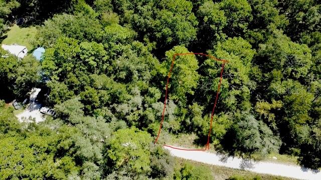 An aerial view shows a wooded lot outlined in red next to a gravel road — 0 NE 138TH TERRACE, WILLISTON, FL