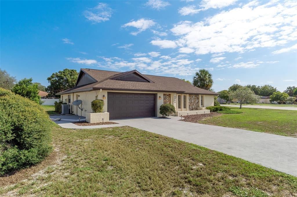 A single-story house with a brown roof, tan stucco walls, and a two-car garage — 9009 HEATHER BOULEVARD, WEEKI WACHEE, FL