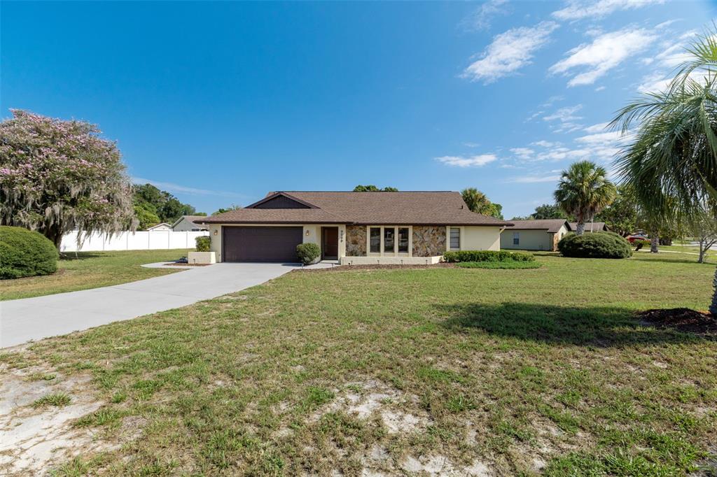 A single-story house with a brown roof, stone facade, and a concrete driveway — 9009 HEATHER BOULEVARD, WEEKI WACHEE, FL