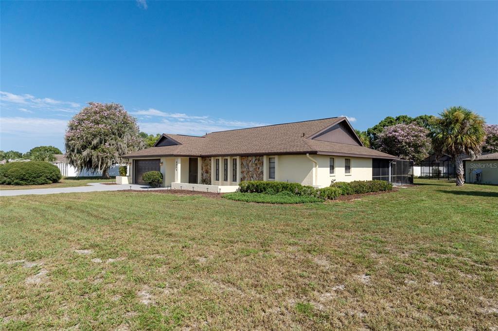 A single-story house with a stone facade, brown roof, and a large front lawn — 9009 HEATHER BOULEVARD, WEEKI WACHEE, FL