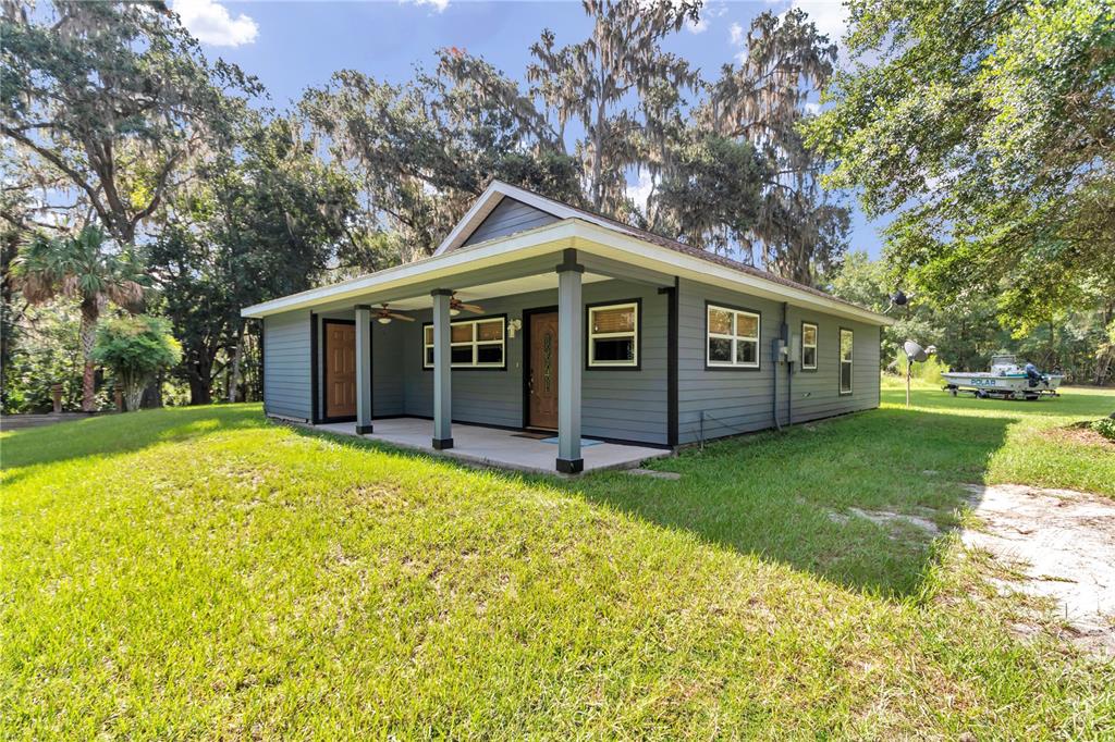 An exterior view of a gray, single-story house with a covered porch and shingled roof — 21497 NW 75TH AVENUE, MICANOPY, FL