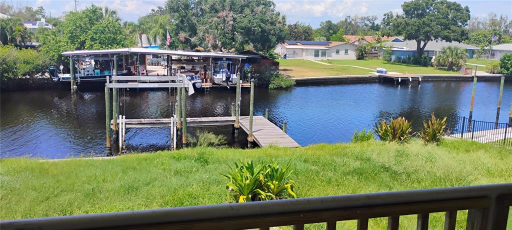 A view of a canal with boat docks and houses from a grassy backyard — 819 BLUE HERON BOULEVARD, RUSKIN, FL