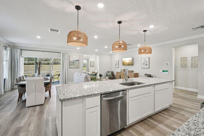 A kitchen island with a granite countertop and stainless steel dishwasher sits in an open-concept room — 5963 LYON ROAD, SPRING HILL, FL