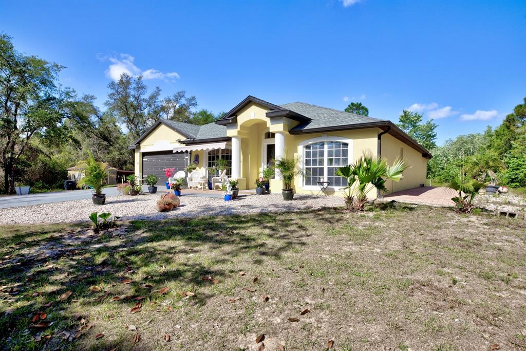 A yellow single-story house with a garage, columns, and a gravel front yard — 2478 THACKER TRAIL, KISSIMMEE, FL