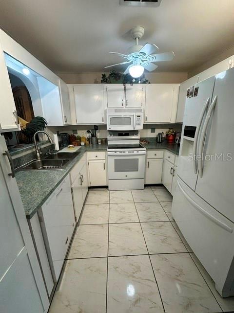 A kitchen features white cabinetry, a white stove, a white refrigerator, and light-colored tiled floors — 4310 VANTAGE CIRCLE, SEBRING, FL