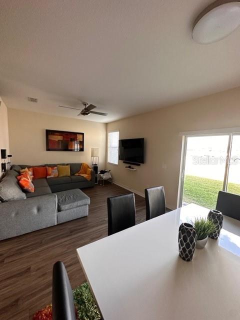 A living room and dining area feature wood-look flooring, a sectional sofa, and a television — 11048 SAVANNAH LANDING CIRCLE, ORLANDO, FL
