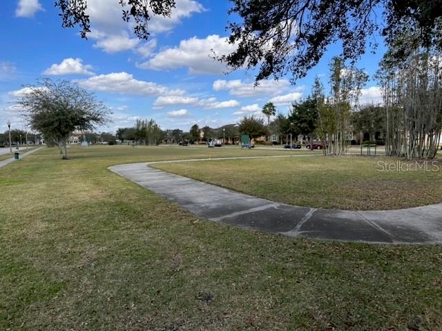 A paved walkway curves through a grassy park area with trees under a blue sky — 11048 SAVANNAH LANDING CIRCLE, ORLANDO, FL