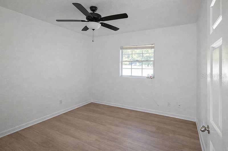 An empty bedroom features white walls, light wood-look flooring, and a ceiling fan — 640 JASMINE ROAD, CASSELBERRY, FL