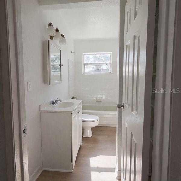 A bathroom features a white vanity, a toilet, and a bathtub with a window — 640 JASMINE ROAD, CASSELBERRY, FL