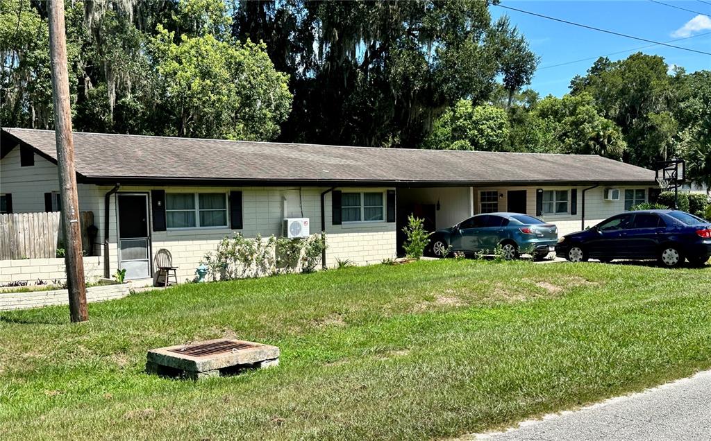 A single-story duplex with a concrete block exterior, a shingled roof, and two parked cars — 5135-5129 UPSON AVENUE, DE LEON SPRINGS, FL