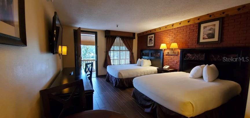 A hotel room features two queen beds, a brick accent wall, and a balcony entrance — 3200 RIVER RANCH BOULEVARD UNIT 225, RIVER RANCH, FL