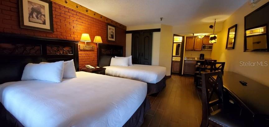 A hotel room features two beds, a brick accent wall, and a small kitchenette area — 3200 RIVER RANCH BOULEVARD UNIT 225, RIVER RANCH, FL