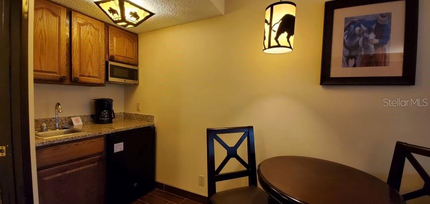 A small kitchenette features wooden cabinets, a sink, a microwave, and a dining table — 3200 RIVER RANCH BOULEVARD UNIT 225, RIVER RANCH, FL