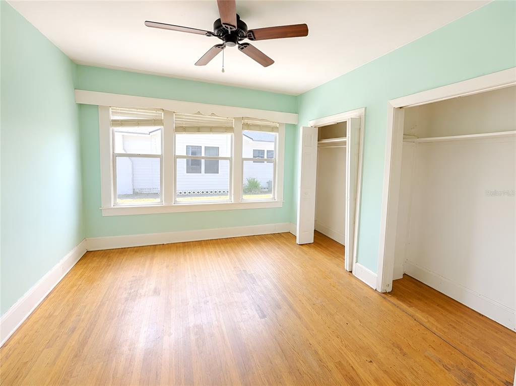 An empty bedroom with orange walls, hardwood floors, a ceiling fan, and white trim — 1037 LEXINGTON STREET, LAKELAND, FL