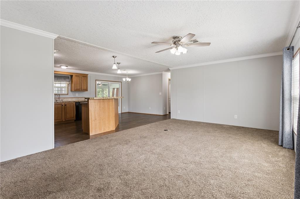 A living room with brown carpet flows into a kitchen featuring wood cabinets and flooring — 33525 LINDA DRIVE, LEESBURG, FL