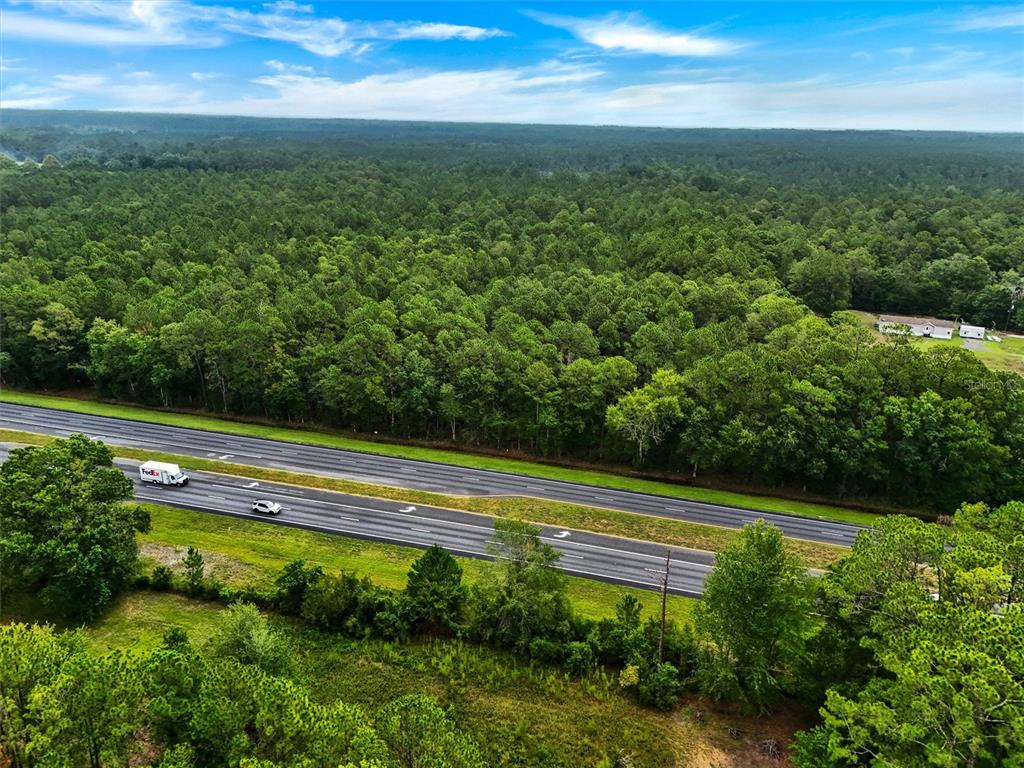 An aerial view shows a multi-lane highway running through a dense forest — TBD NE NE 6TH AVENUE, LAWTEY, FL