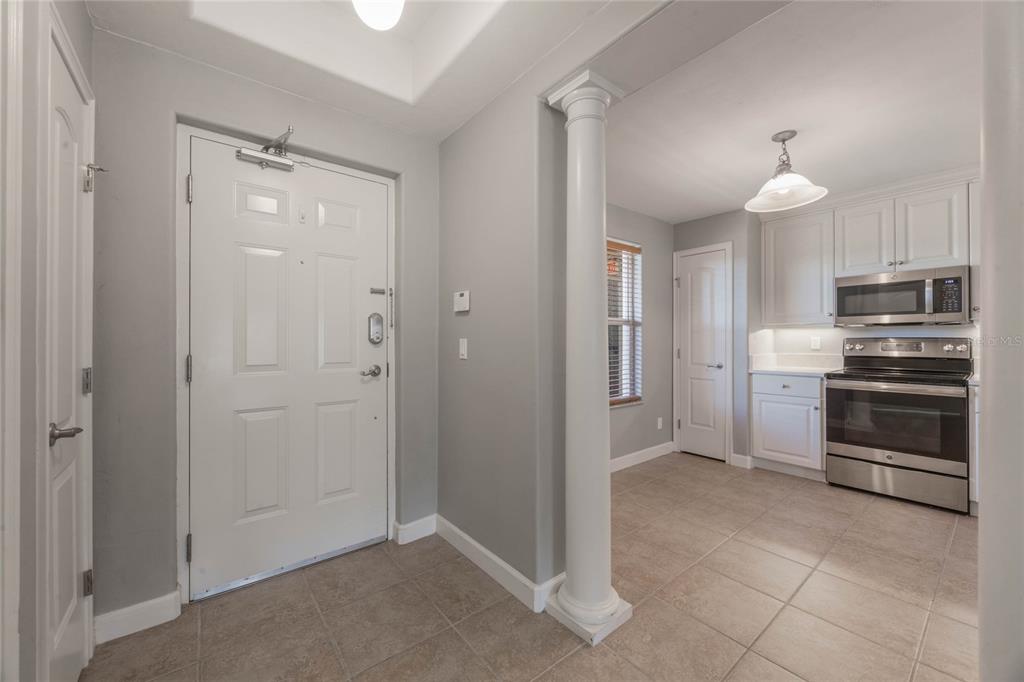 A tiled entryway with a white door leads to a kitchen featuring stainless steel appliances — 424 LUNA BELLA LANE UNIT 332, NEW SMYRNA BEACH, FL