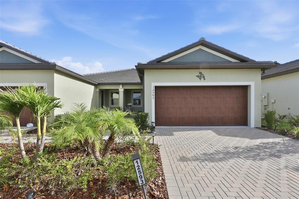 A single-story house features a brown garage door, a paved driveway, and palm trees — 12593 LILY QUARTZ LOOP, PARRISH, FL