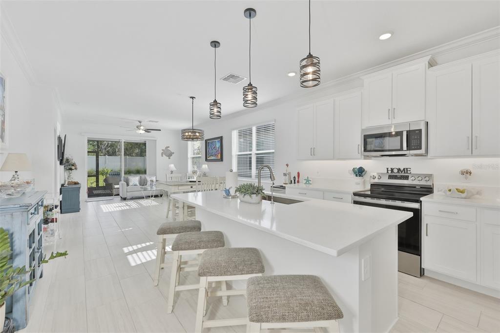 A swimming pool with lounge chairs on a paved deck surrounded by palm trees — 12593 LILY QUARTZ LOOP, PARRISH, FL