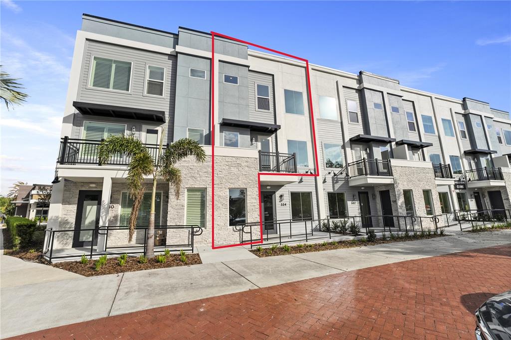 A multi-story townhouse exterior features gray siding, stone veneer, and a small balcony — 336 CENTER LAKE LANE UNIT 336, OVIEDO, FL