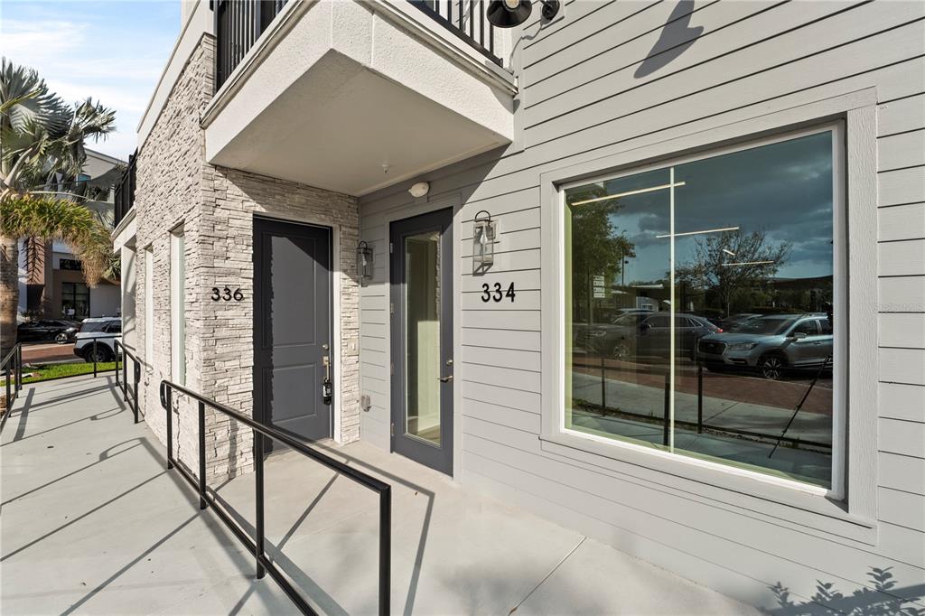 The exterior of a building features two gray doors, stone siding, and a large window — 336 CENTER LAKE LANE UNIT 336, OVIEDO, FL