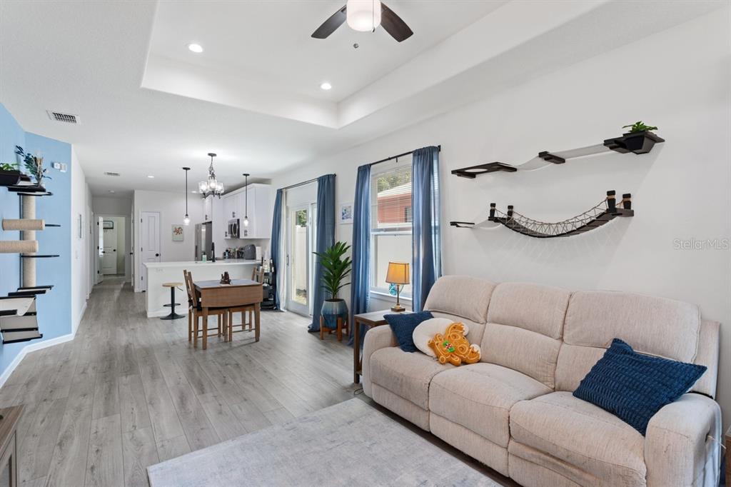 A living room with a beige sofa, cat wall furniture, and an open-concept kitchen — 1967 VIRGINIA AVENUE, EUSTIS, FL