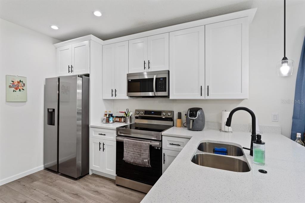 A kitchen features white cabinets, stainless steel appliances, and a light-colored quartz countertop — 1967 VIRGINIA AVENUE, EUSTIS, FL