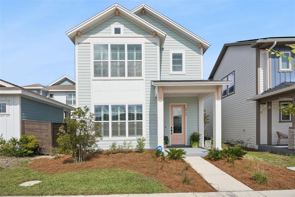 A two-story house with light blue siding, a covered front porch, and a pink door — 2954 JOURNEY PLACE, ST CLOUD, FL