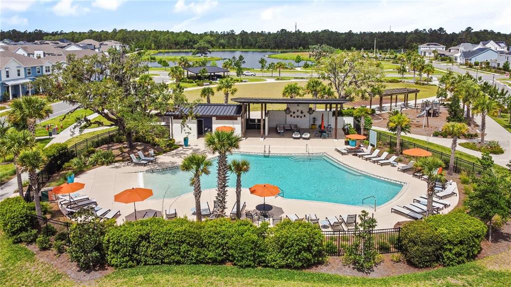 An aerial view of a community swimming pool with lounge chairs, umbrellas, and a pavilion — 2954 JOURNEY PLACE, ST CLOUD, FL