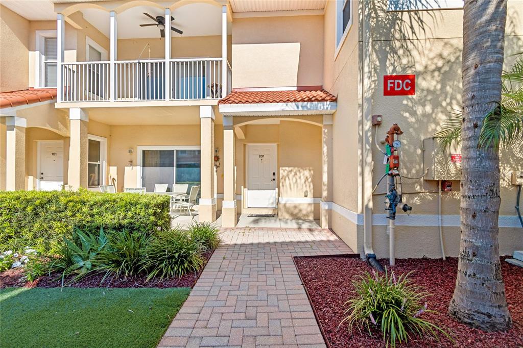 An exterior view of a two-story apartment building with a brick walkway and fire connection — 21041 SUNPOINT WAY UNIT 201, LUTZ, FL