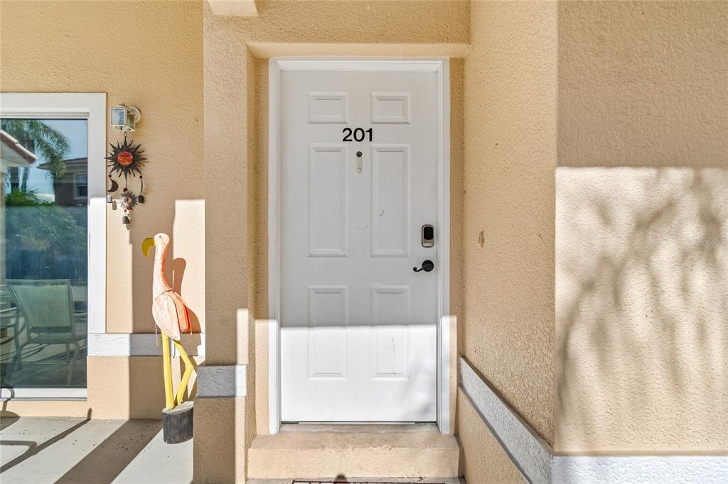 A white front door marked with the number 201 stands beside a decorative flamingo statue — 21041 SUNPOINT WAY UNIT 201, LUTZ, FL