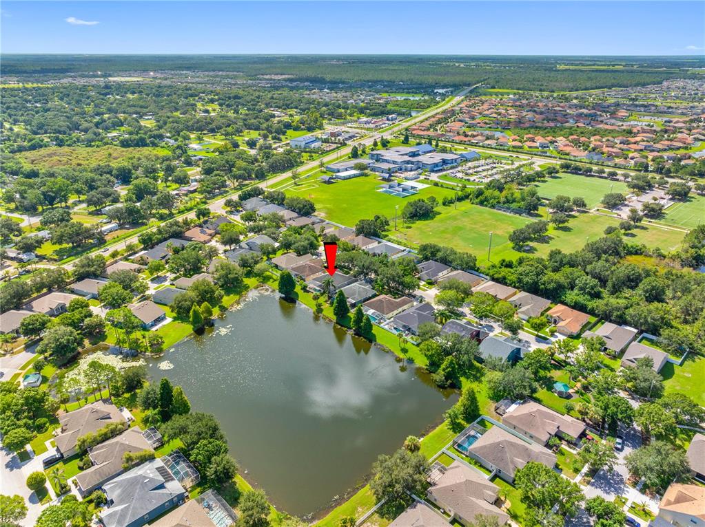 An aerial view shows a suburban neighborhood with houses surrounding a central pond — 11916 SUMMER SPRINGS DRIVE, RIVERVIEW, FL