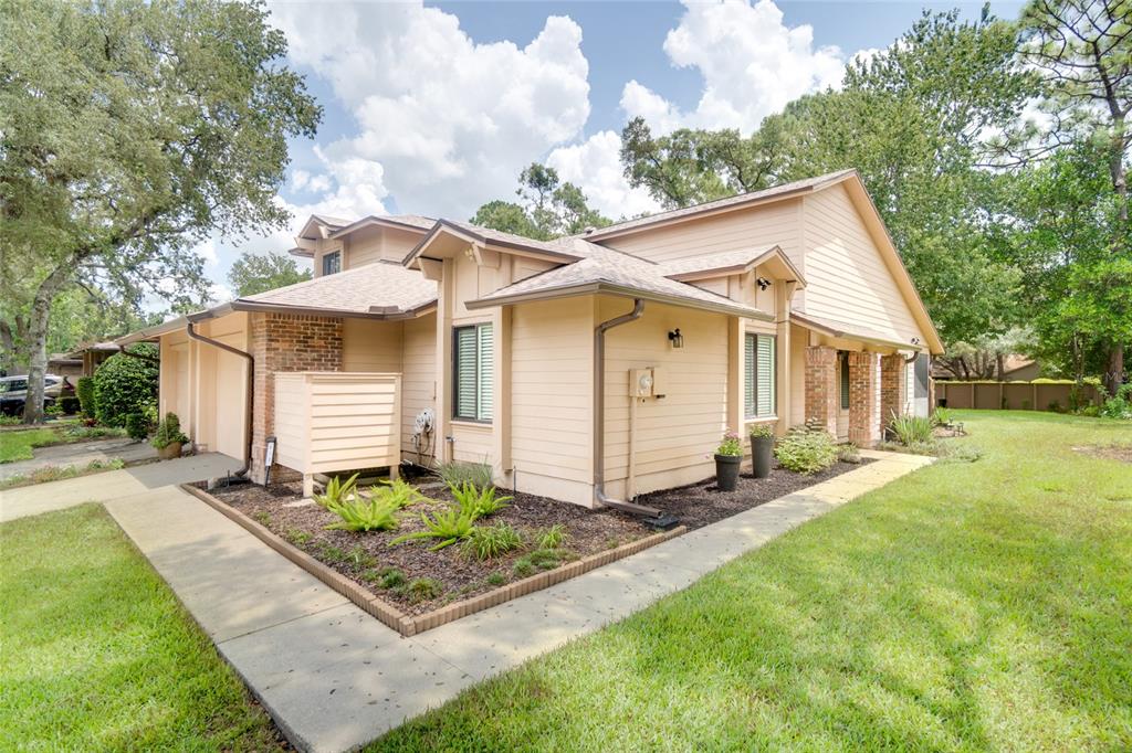 A tan-sided house with a brick chimney and a concrete walkway in a grassy yard — 419 NEWTON PLACE, LONGWOOD, FL