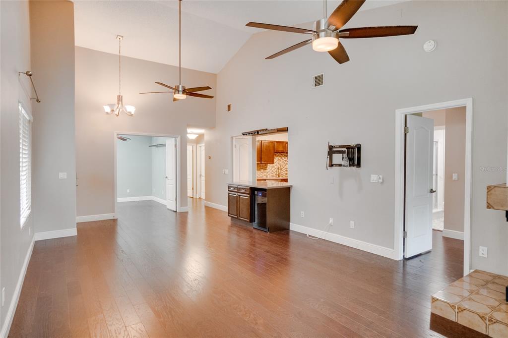A living area with vaulted ceilings, hardwood floors, a ceiling fan, and a kitchen pass-through — 419 NEWTON PLACE, LONGWOOD, FL