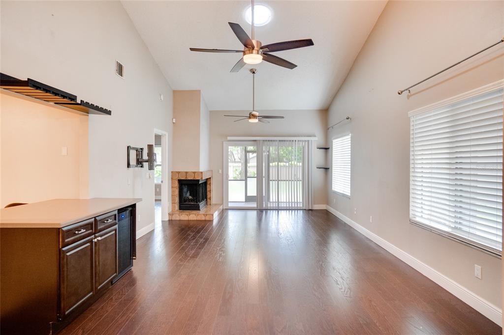 A living room with dark wood floors, a fireplace, two ceiling fans, and sliding glass doors — 419 NEWTON PLACE, LONGWOOD, FL