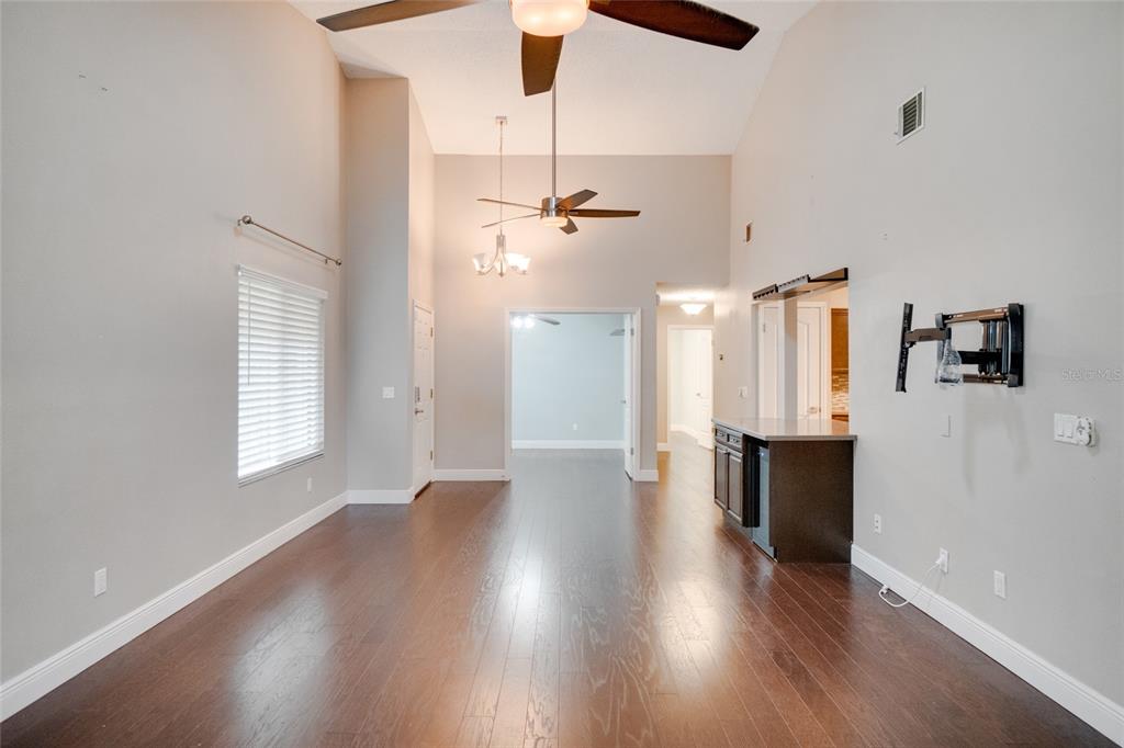 A living room with high ceilings, dark hardwood floors, a ceiling fan, and a wet bar — 419 NEWTON PLACE, LONGWOOD, FL