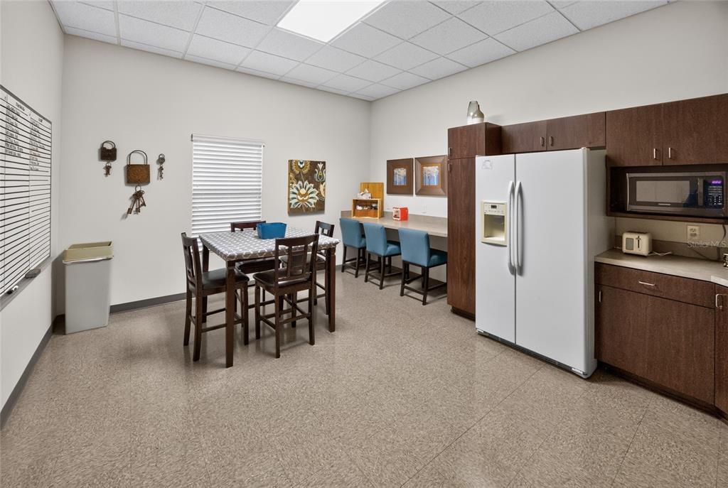 A breakroom features a dining table, a breakfast bar with blue stools, and a refrigerator — 840 & 842 HIGHWAY 466, LADY LAKE, FL