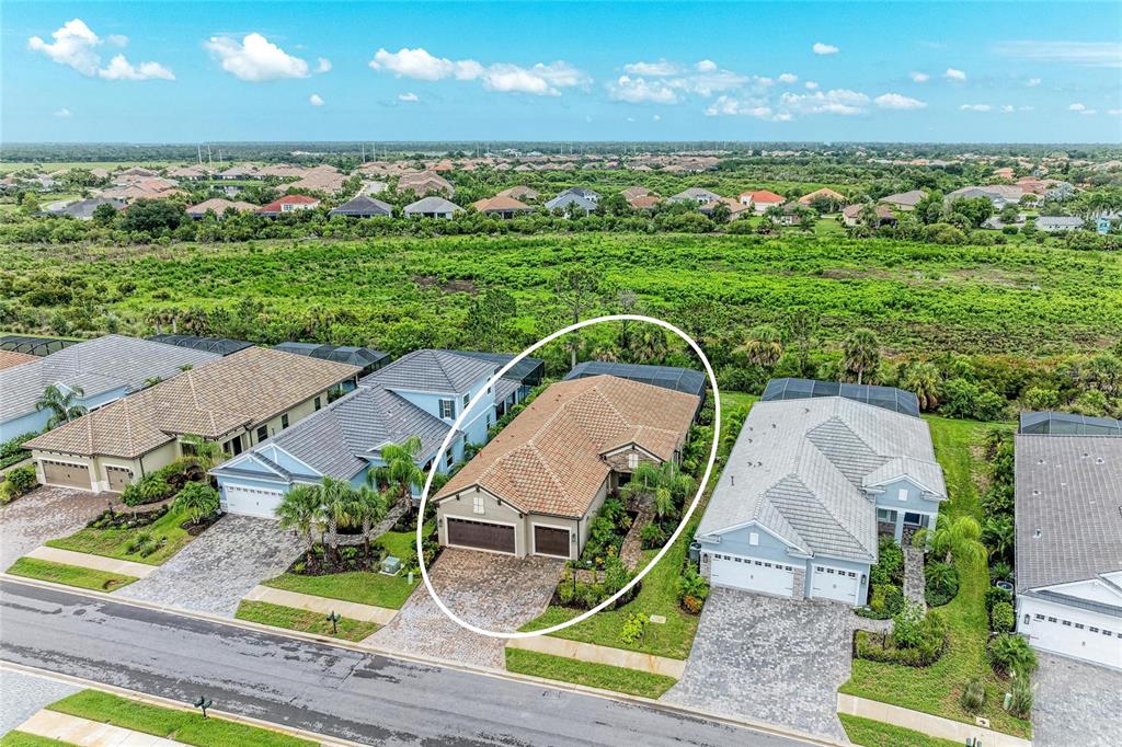 An aerial view of a single-story suburban house with a tiled roof and paver driveway — 10913 TREVINO STREET, ENGLEWOOD, FL