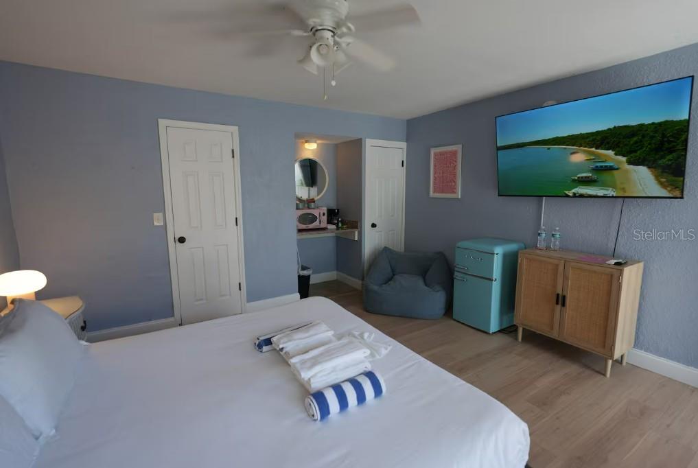 A bedroom features a bed, a wall-mounted television, a blue mini-fridge, and a beanbag chair — 345 HAMDEN DRIVE, CLEARWATER BEACH, FL